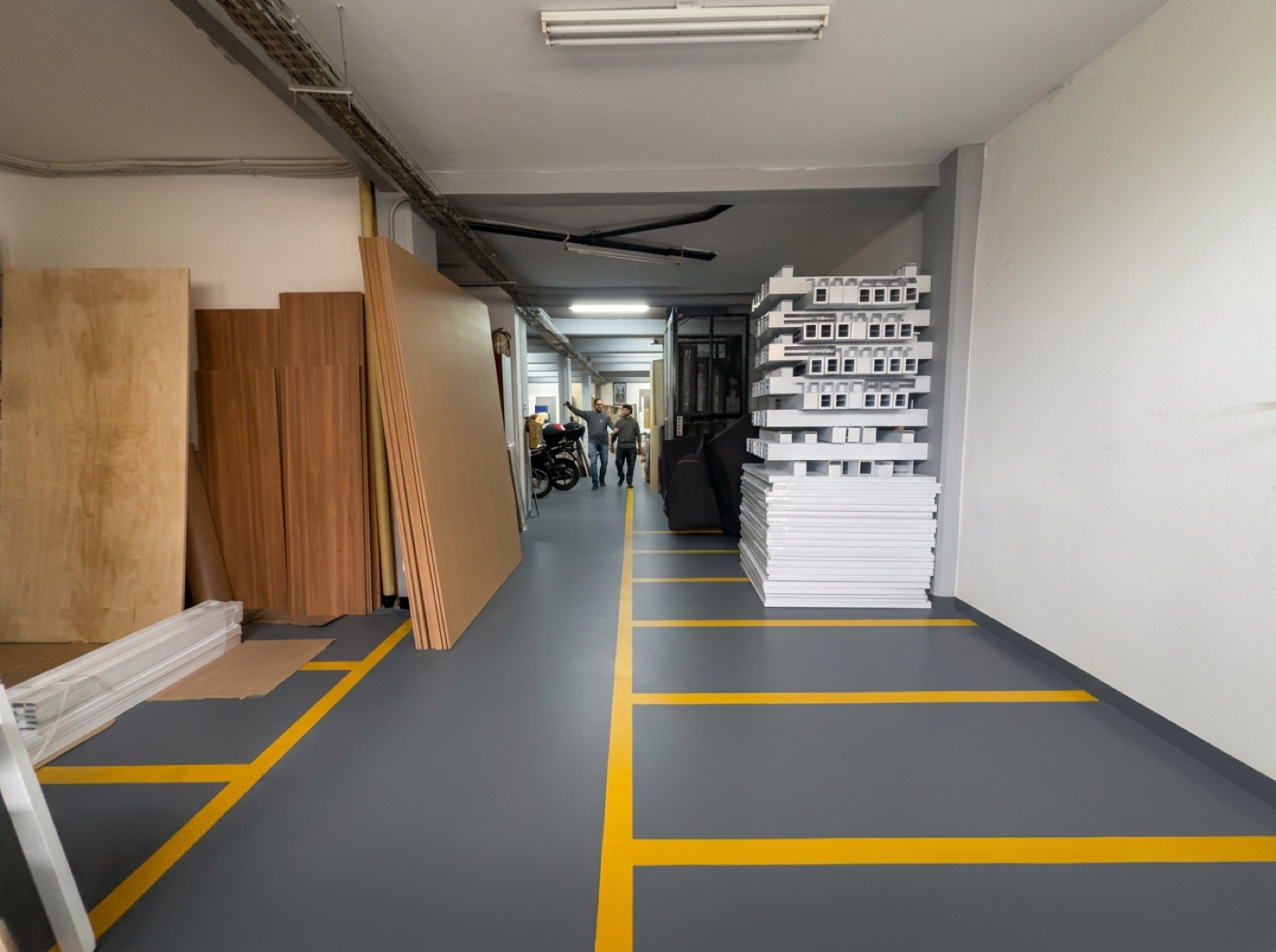 Pasillo del taller con tableros, herrajes y perfiles almacenados